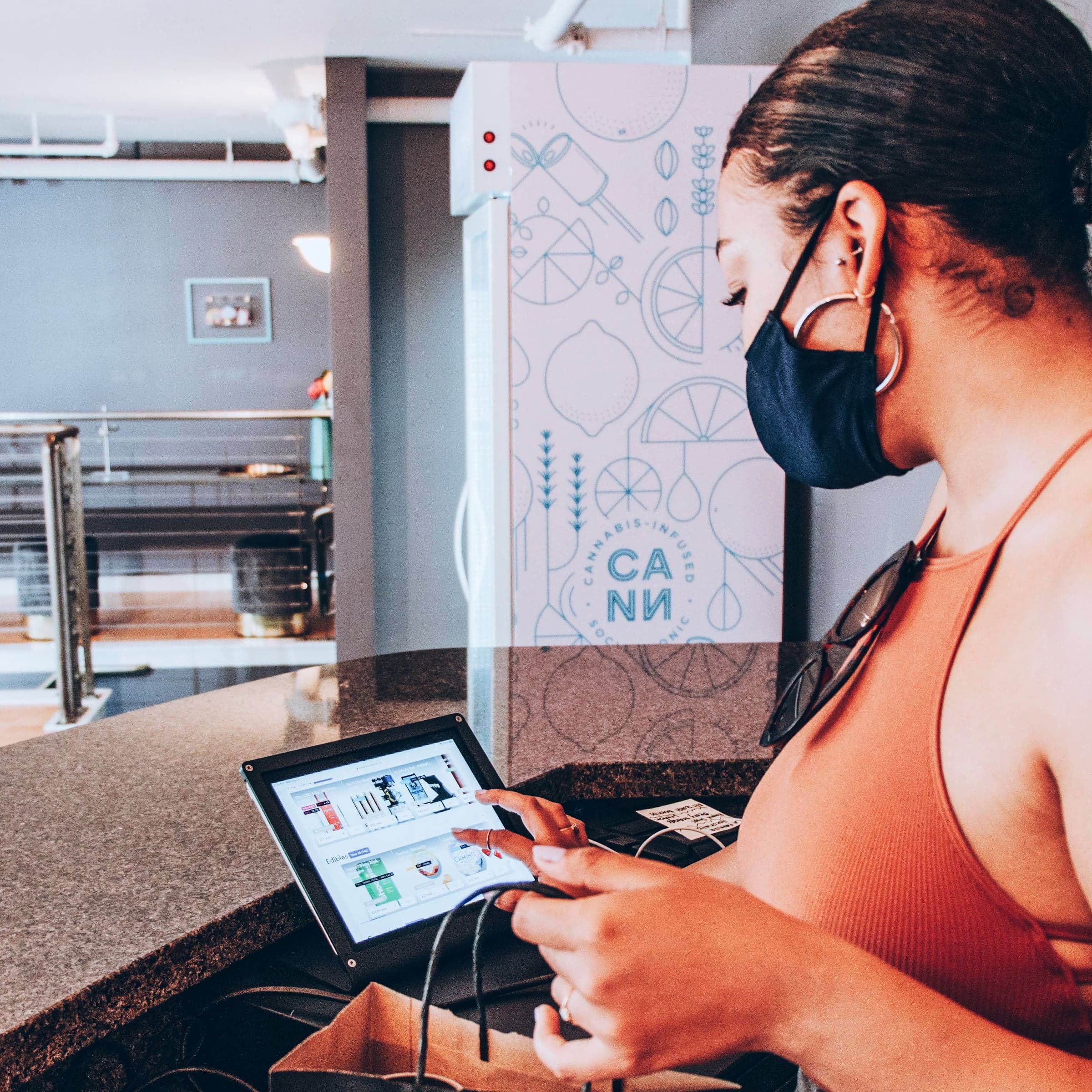 A woman holds a bag of cannabis products while using Meadow's cannabis POS
