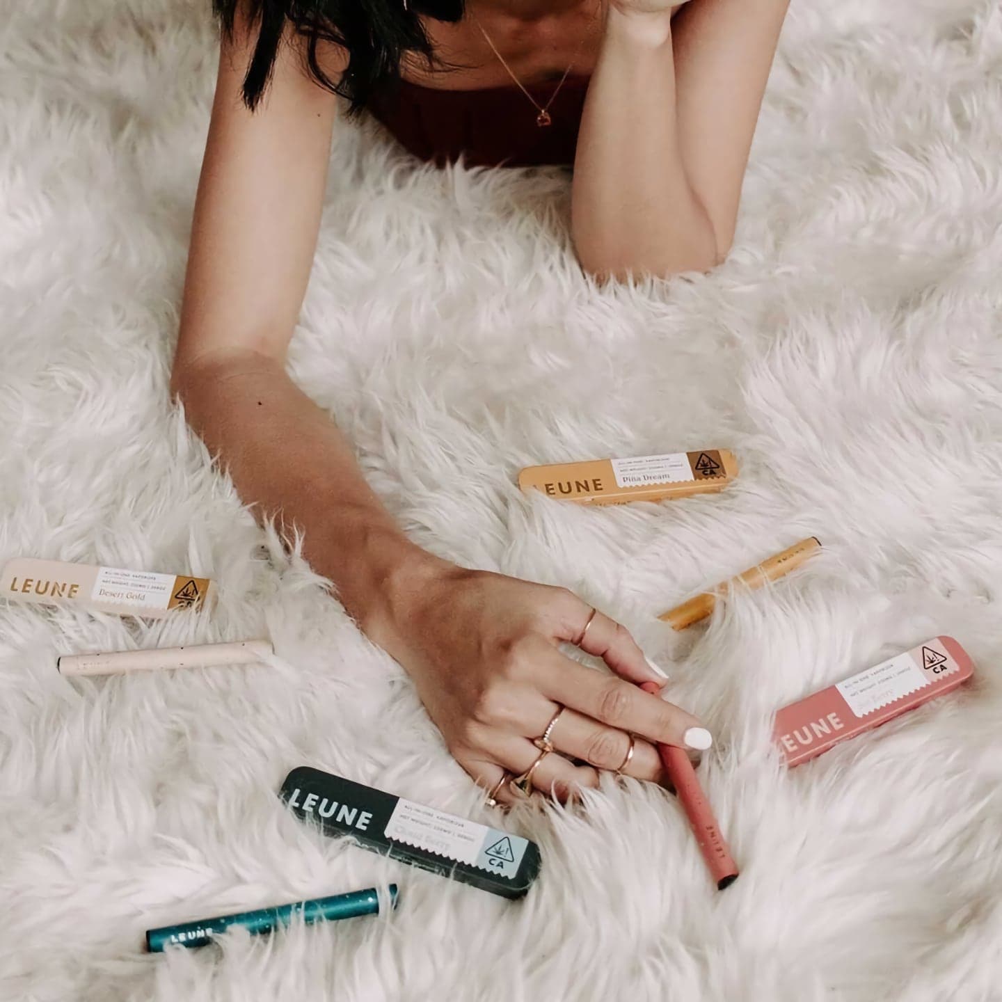 A woman on a fuzzy blanket looking through Leune products