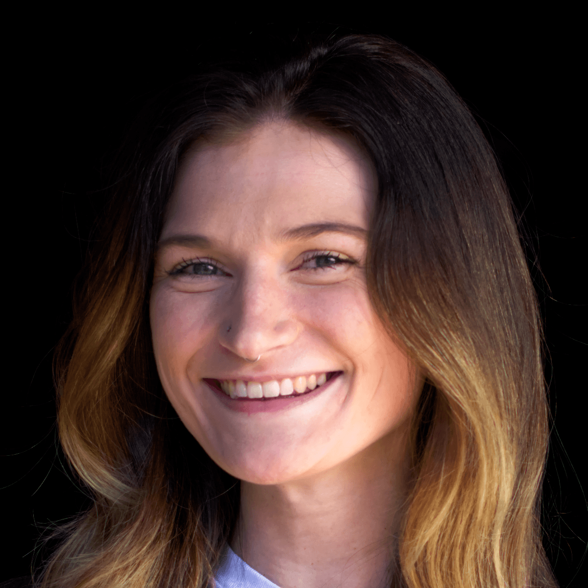 A smiling woman with fair skin and long dark highlighted hair.