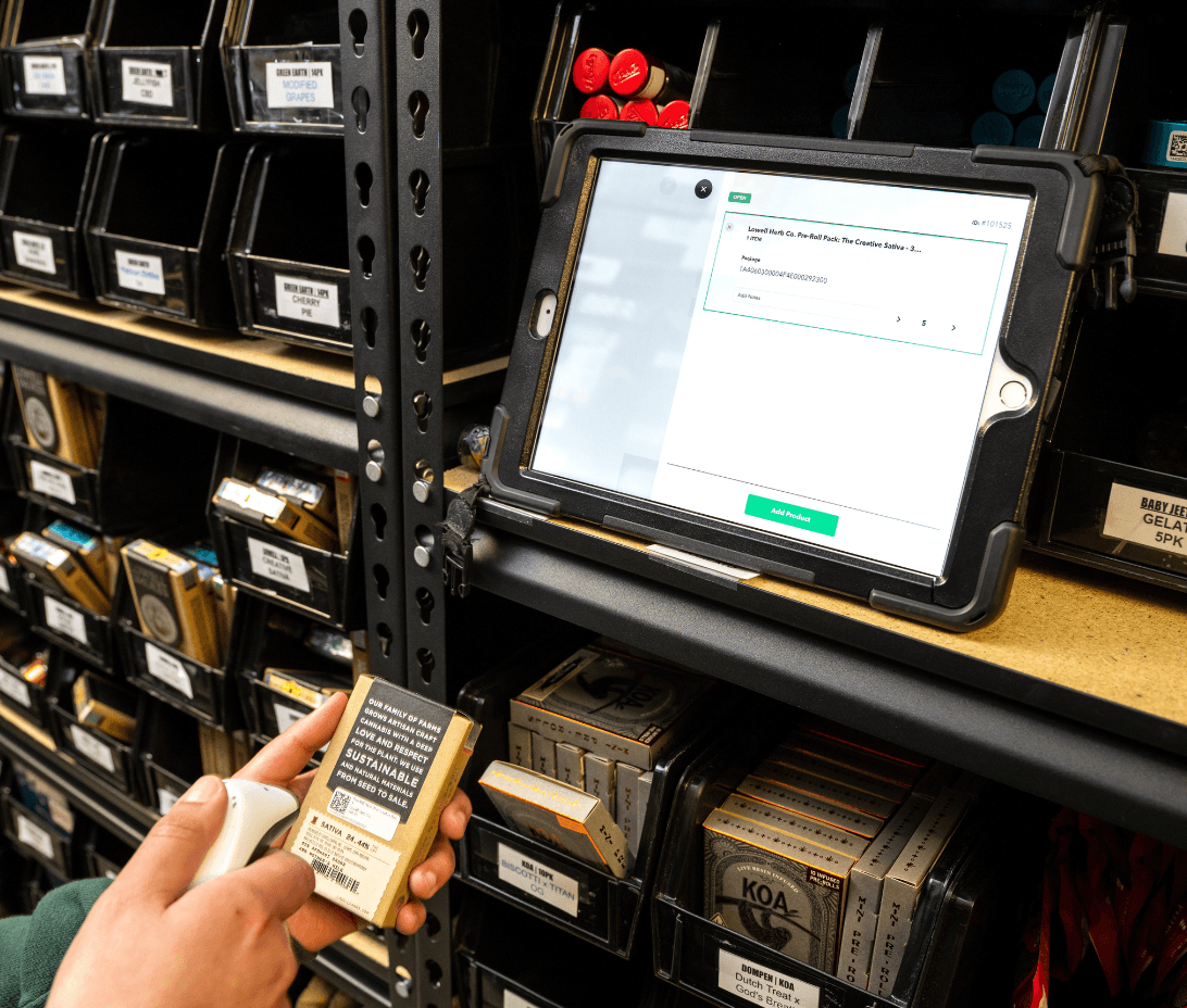 A dispensary staff member scans a cannabis product in front of organized inventory bins, with Meadow’s inventory management software displayed on a mounted tablet. The screen shows product intake details, demonstrating real-time tracking and compliance support for METRC in Massachusetts.
A dispensary staff member scans a cannabis product in front of organized inventory bins, with Meadow’s inventory management software displayed on a mounted tablet. The screen shows product intake details, demonstrating real-time tracking and compliance support for METRC in Massachusetts.