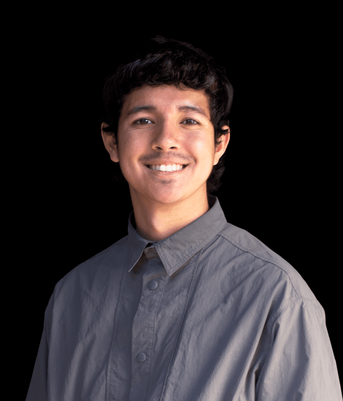 A smiling young man with black hair, wearing a gray-blue collared shirt.