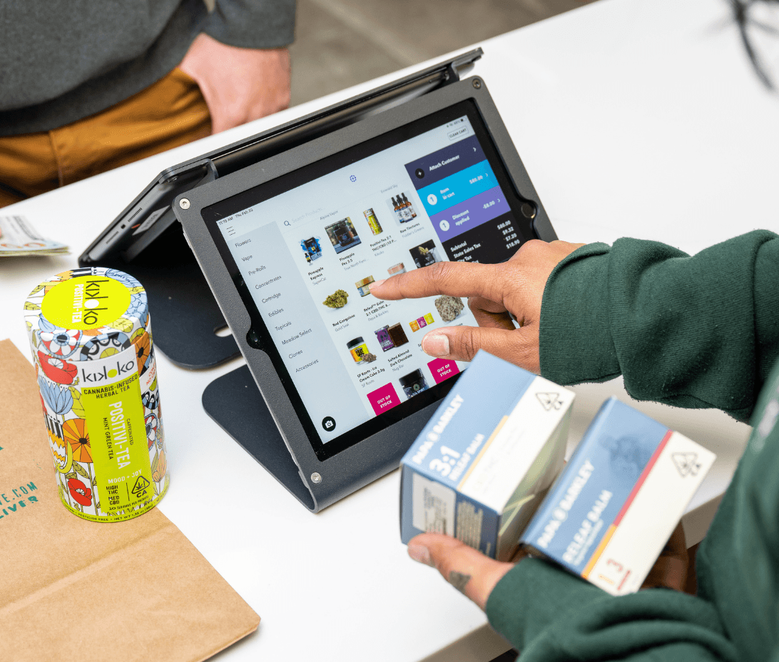 Inside a bustling dispensary, a friendly budtender is completing a sale using Meadow's advanced POS software. The scene is set at a modern, clean checkout counter where the budtender, equipped with a sleek, user-friendly touchscreen device, is shown finalizing a customer's purchase. The POS interface is clearly displayed, showcasing an easy-to-navigate menu.
This image captures the simplicity and efficiency of Meadow's integrated platform, illustrating how it serves as a comprehensive solution for dispensary operations. It showcases the ease with which sales are processed, menus and inventory are managed, and how effortlessly data can be pushed to accounting software like QuickBooks. The overall impression is one of a streamlined, hassle-free retail experience, both for the staff and the customers, made possible by Meadow's single source of truth for all operational needs.